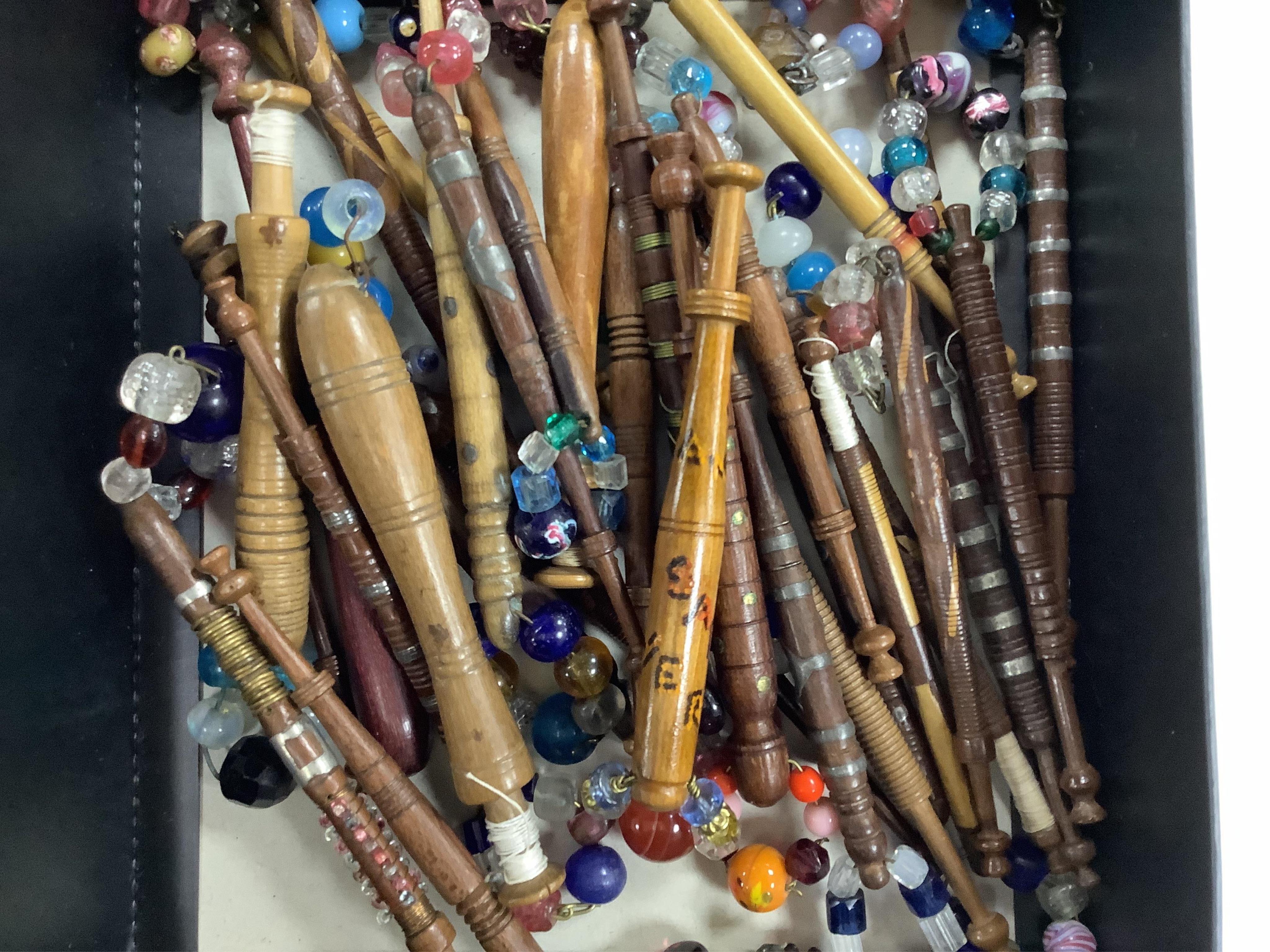 A collection of mostly 19th and 20th century ornate bone lace making bobbins, with coloured beaded ends, together with a similar smaller selection of wooden bobbins. Condition - good